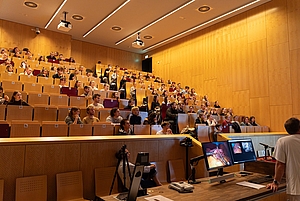 Viele Personen in einem Hörsaal schauen gespannt nach vorn.