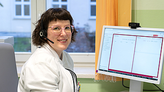 Lächelnde Frau mit Headset vor Computer
