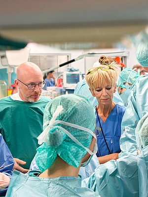 Gruppe von medizinischem Personal in Operationskleidung bei einer Operation im OP-Saal
