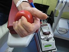Hand mit rotem Ball und Blutabnahmeausstattung