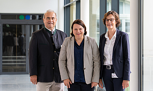 Drei Personen in einem modernen lichtdurchflueteten Krankenhausflur
