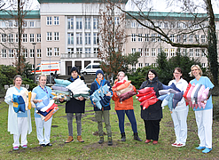 Gruppe steht im Patientengarten mit Kissen in der Hand