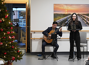 Ein Tannenbaum auf der linken Seite, ein Gitarrist und eine Sängerin.