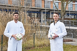 Dr. Schlees und Dr. Darowski im weißen Kittel mit Fußball in der Hand.