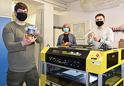 Paul Henke, Dr. Kirsten Peters und Christopher Heiden stehen an einem 3D-Drucker