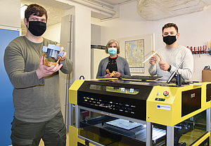 Paul Henke, Dr. Kirsten Peters und Christopher Heiden stehen an einem 3D-Drucker