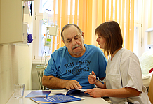 Pflegerin mit älterem Patienten am Tisch