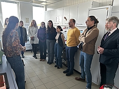 Mehrere Schüler und Erwachsene stehen in einem laborähnlichen Raum