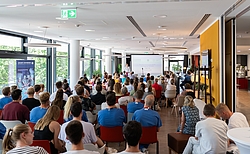 Viele Menschen in einem Raum blicken auf eine Präsentation