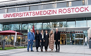 Fünf Personen stehen vor dem Haupteingang der Universitätsmedizin Rostock.