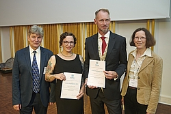 Zwei Männer und zwei Frauen bei Auszeichnung mit Urkunde in der Hand