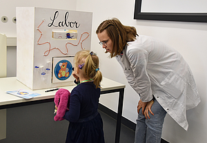 Medizinstudentin mit Mädchen vor Karton als Labor