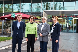 Vier Personen stehen nebeneinander vor dem Haupteingang der Universitätsmedizin Rostock.