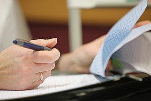 Hand mit Stift über Block auf Klemmbrett