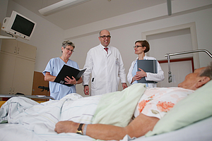 Ein Arzt und zwei Schwestern an einem Patientenbett