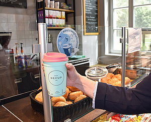 Hand mit Mehrweg-Kaffeebecher