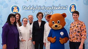 Eine Gruppe von Menschen steht vor einer bedruckten Wand