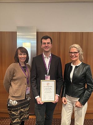 3 lächelnde Personen stehen nebeneinander