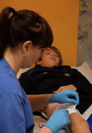 Eine Ärztin wechselt einem Kind den Verband.