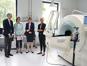 Vier Personen im Businesslook stehen in einem modern anmutenden Raum vor einem medizinischen Großgerät.