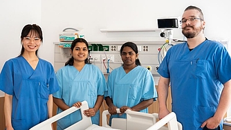 4 Personen stehen in einem Krankenhauszimmer nebeneinander