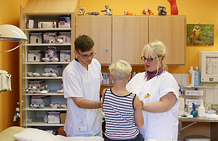 Ärztin und Pfleger untersuchen Kind