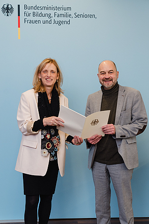 Eine Person übergibt einer anderen eine Urkunde