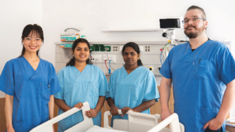 4 Personen stehen in einem Krankenhauszimmer nebeneinander