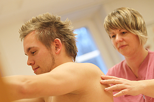 Physiotherapeutin bei der Behandlung eines jungen Mannes