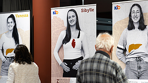 2 Menschen vor 3 Plakaten