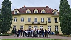 Eine Gruppe Personen vor einem gelben Gebäude.