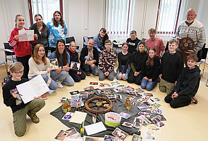 Schüler und Dozenten sitzen im Halbkreis. Vor ihnen liegen viele Bilder zum Thema Mut und ein großes Steuerrad